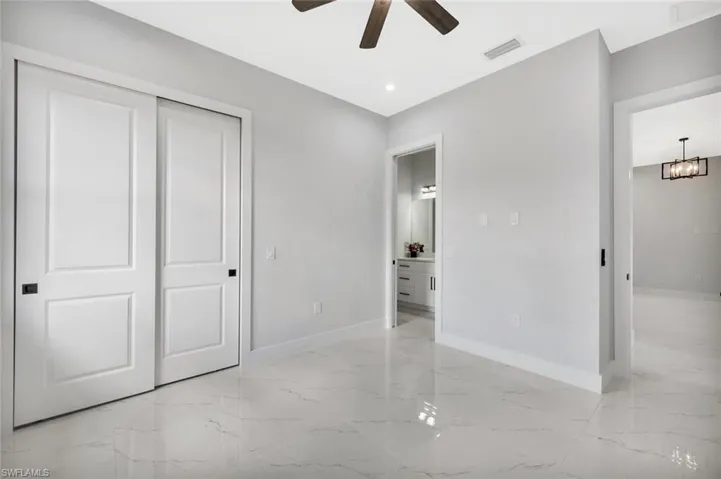 Unfurnished bedroom with light marble finish flooring, a closet, a ceiling fan, and recessed lighting