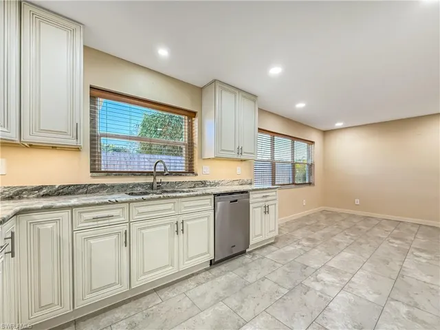 Kitchen featuring cream cabinets, dishwasher, light stone counters, and recessed lighting