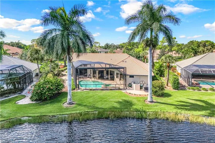 Rear view of property with a lanai, a water view, and a yard