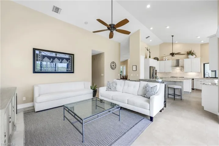 Living room featuring light tile patterned floors, ceiling fan, and high vaulted ceiling