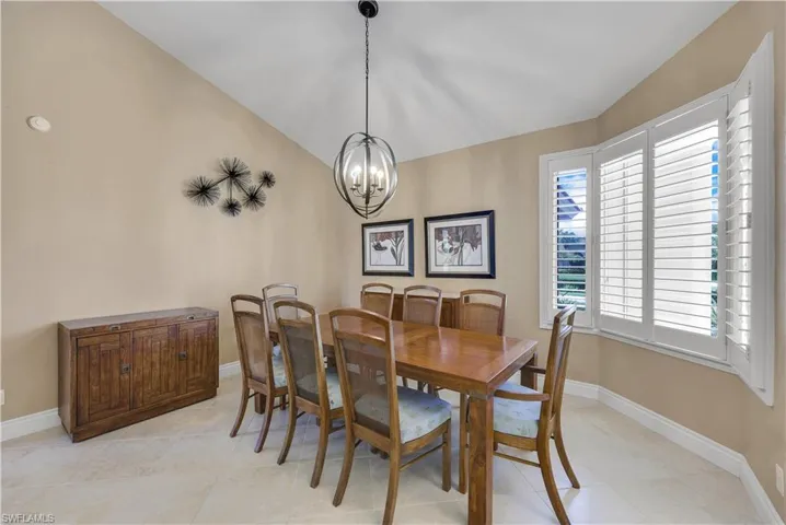 Tiled dining space featuring an inviting chandelier and vaulted ceiling