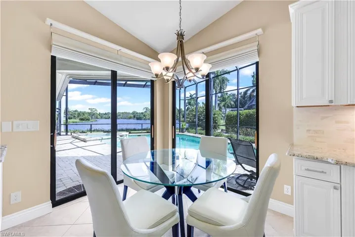 Dining area with light tile patterned flooring, an inviting chandelier, vaulted ceiling, and a wealth of natural light