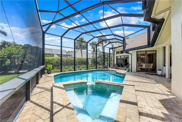 View of pool with glass enclosure and a patio area