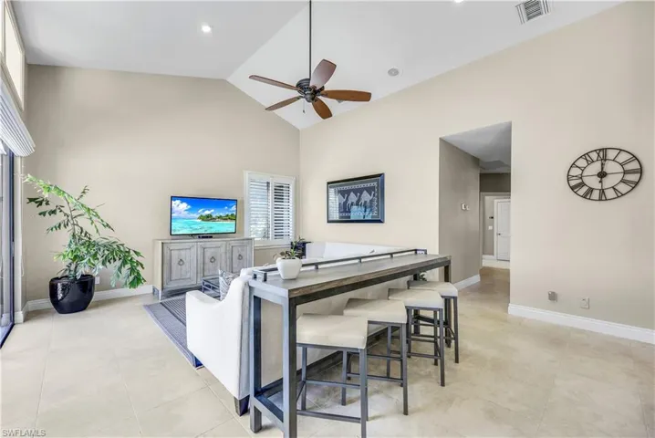 Living room with light tile patterned flooring, ceiling fan, and high vaulted ceiling