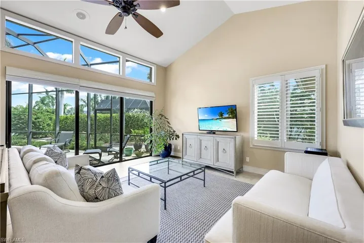 Living room with high vaulted ceiling, a wealth of natural light, and ceiling fan