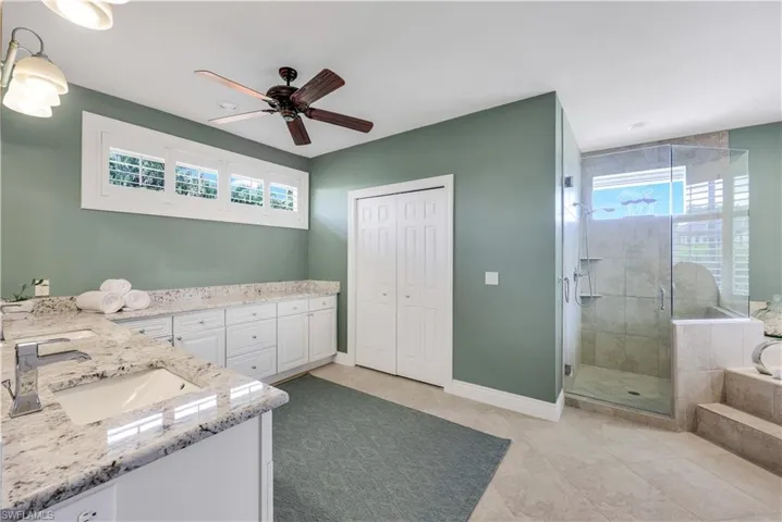 Bathroom featuring tile patterned flooring, ceiling fan, independent shower and bath, and vanity