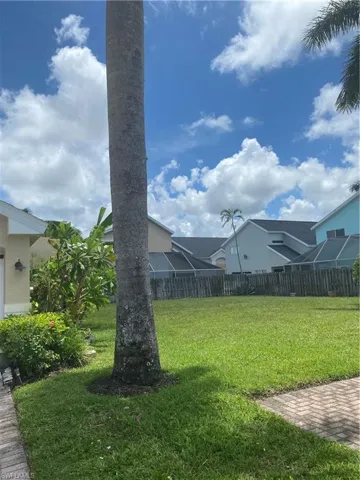 Expansive grass area with a mature palm tree and brick paver walkway