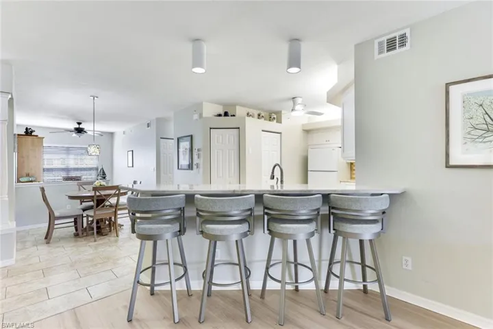 Kitchen with ceiling fan, freestanding refrigerator, a peninsula, and a kitchen bar