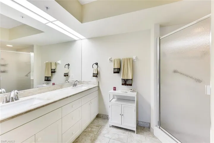Full bathroom featuring double vanity, a shower stall, and tile patterned flooring