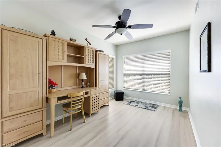 Office space with a ceiling fan, light wood finished floors, and built in desk