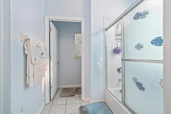 Bathroom featuring tile patterned flooring and shower / bath combination with glass door