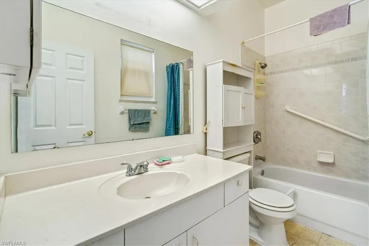 Full bathroom with tile patterned floors, shower / bath combo, vanity, and toilet