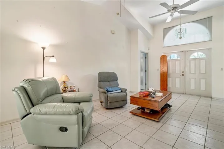 Living room with light tile patterned floors, a towering ceiling, and ceiling fan