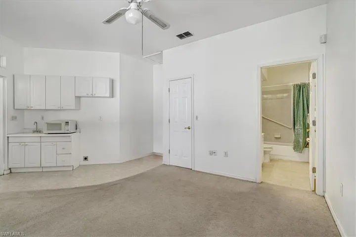 Unfurnished living room with light carpet, ceiling fan, and sink