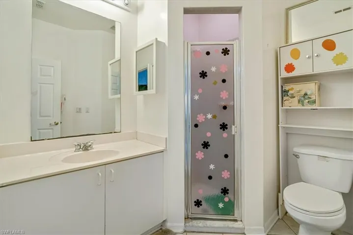Bathroom featuring vanity, a shower, toilet, and tile patterned floors