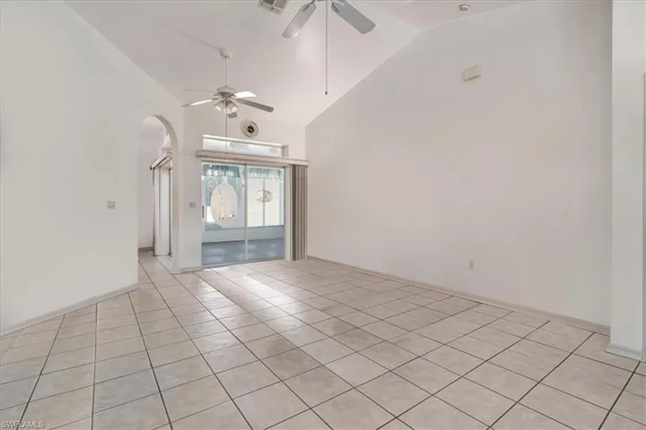 Tiled empty room with high vaulted ceiling and ceiling fan