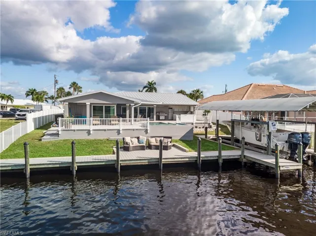 Dock area featuring a fenced in pool, fence private yard, a water view, and a lawn