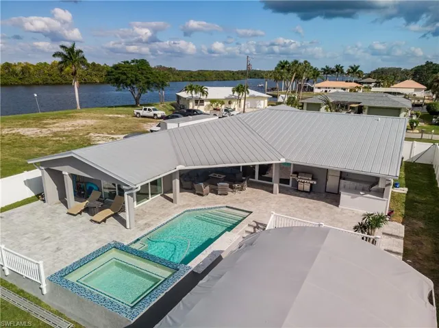 View of pool with a patio area, a water view, a fenced backyard, an outdoor living space, and a pool with connected hot tub