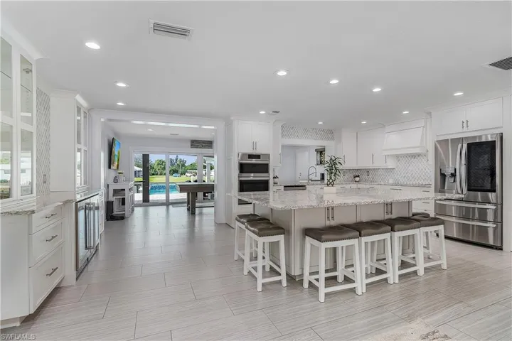 Kitchen featuring decorative backsplash, appliances with stainless steel finishes, a sink, white cabinetry, and visible vents