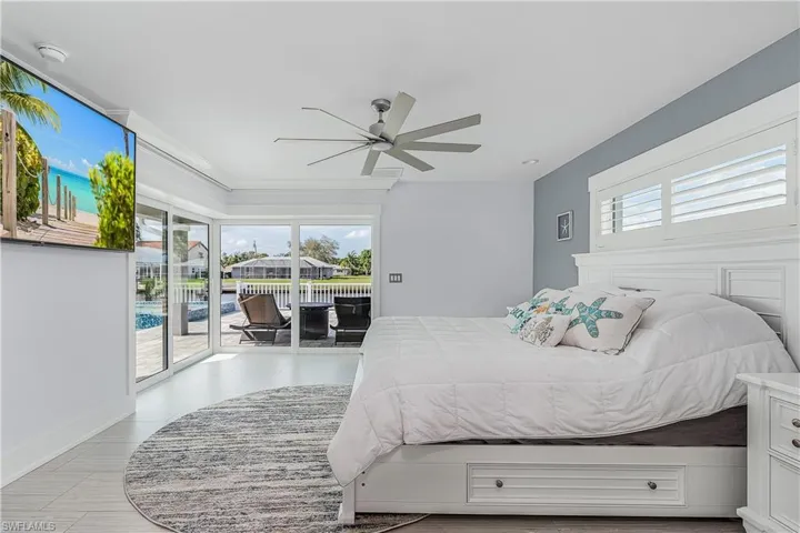 Bedroom featuring a ceiling fan, multiple windows, and access to outside