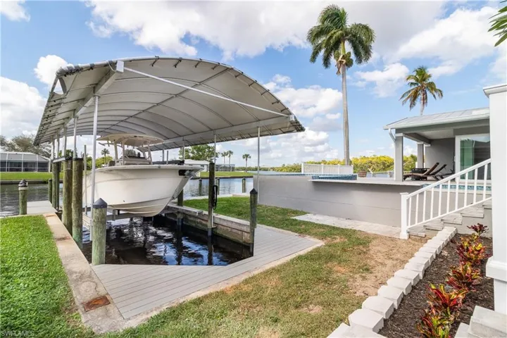 View of dock featuring a pool, a water view, and boat lift