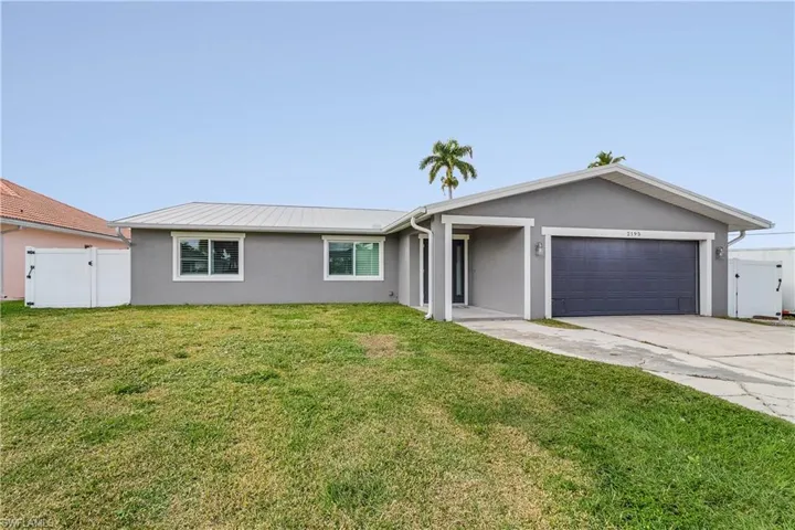 Ranch-style home with stucco siding, fence, a front yard, concrete driveway, and an attached garage