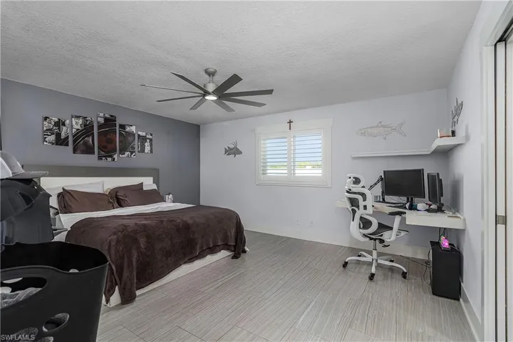 Bedroom featuring a textured ceiling, a ceiling fan, and baseboards
