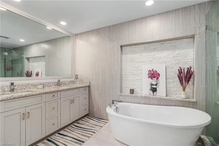 Full bathroom featuring a sink, a freestanding tub, a stall shower, double vanity, and visible vents