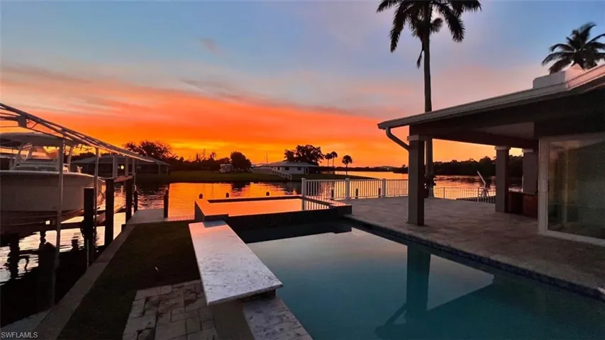 View of swimming pool with a boat dock, boat lift, a water view, fence, and a pool with connected hot tub