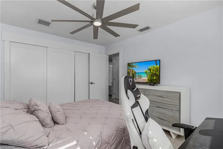 Bedroom featuring wood finished floors, visible vents, a ceiling fan, and a closet