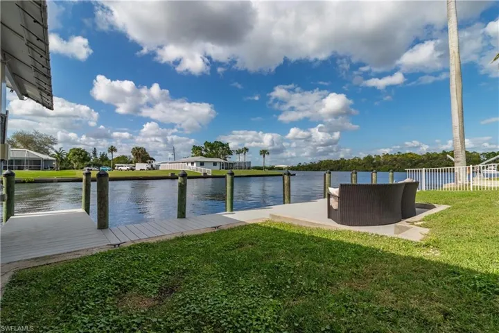 View of dock with fence, a yard, and a water view