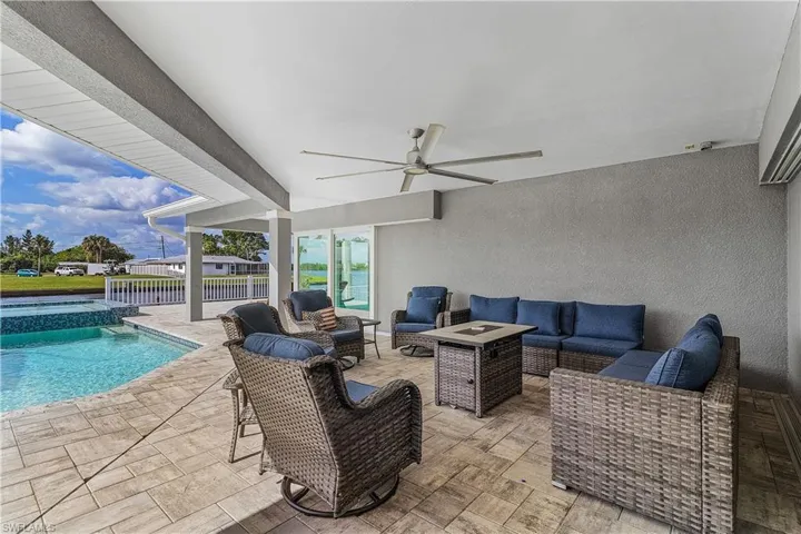 View of patio featuring outdoor lounge area, ceiling fan, a pool with connected hot tub, and fence