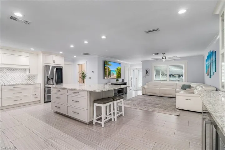 Kitchen with ornamental molding, visible vents, stainless steel refrigerator with ice dispenser, and a kitchen island