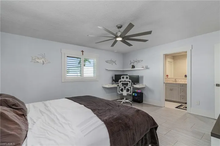 Bedroom featuring a textured ceiling, connected bathroom, a ceiling fan, and baseboards