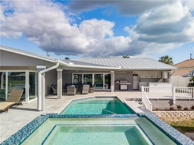 Rear view of property with a pool with connected hot tub, outdoor dining area, exterior kitchen, and a patio area