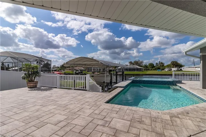 View of swimming pool featuring fence, a patio area, and a pool with connected hot tub