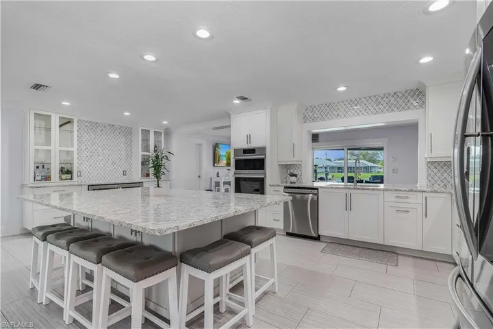 Kitchen featuring white cabinetry, stainless steel appliances, and decorative backsplash