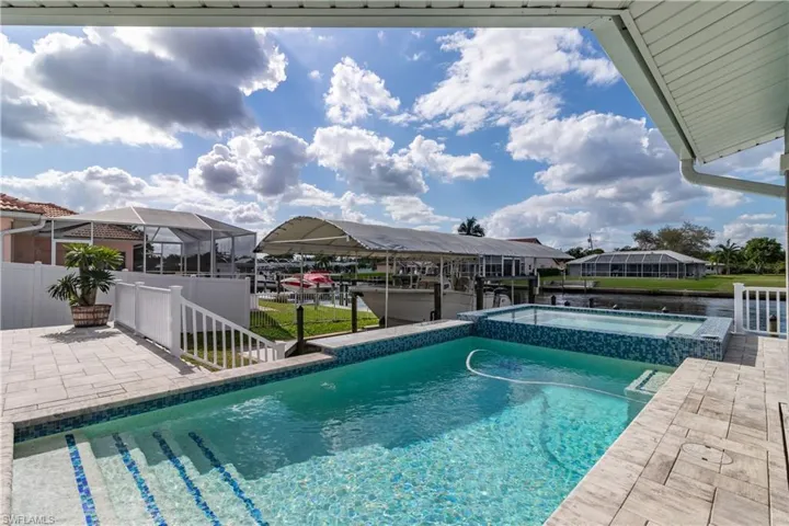 View of swimming pool with a patio, a boat dock, boat lift, and a pool with connected hot tub