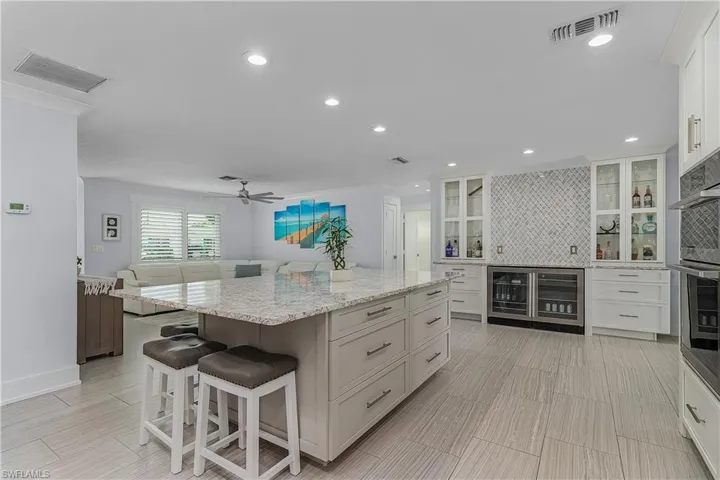 Kitchen featuring a center island, wine cooler, visible vents, and backsplash