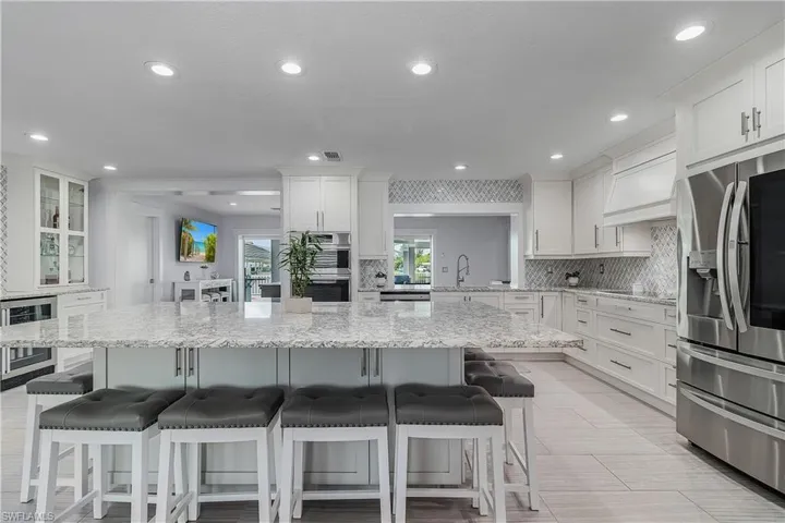 Kitchen with white cabinets, a sink, appliances with stainless steel finishes, a breakfast bar, and backsplash