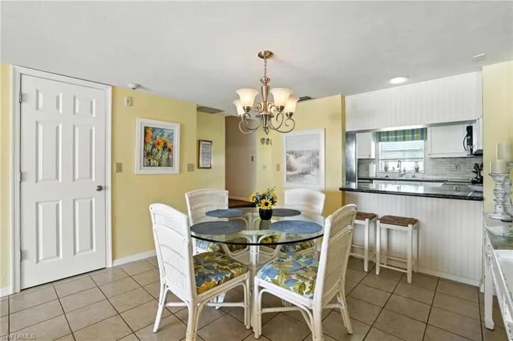 Dining area featuring light tile patterned floors and a chandelier - Virtually Edited Image