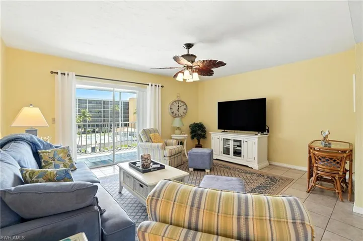Living room featuring light tile patterned floors and a ceiling fan - Virtually Edited Image