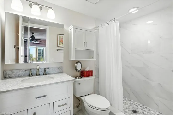 Bathroom featuring vanity, a shower stall, and a ceiling fan - Virtually Edited Image