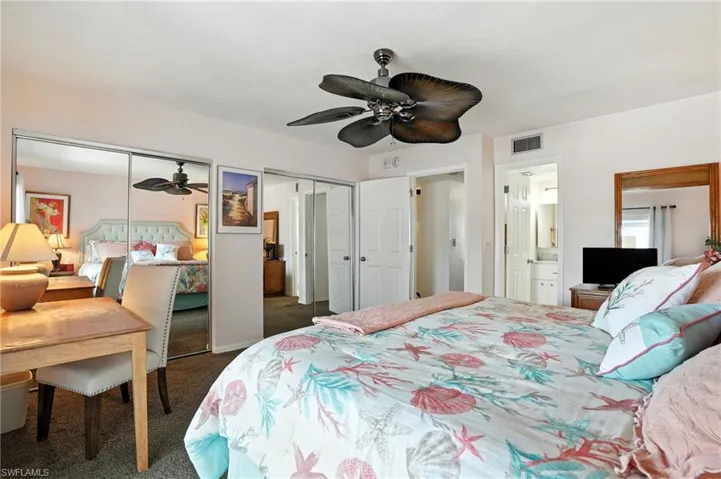 Bedroom with multiple closets, carpet, ensuite bathroom, and a ceiling fan - Virtually Edited Image
