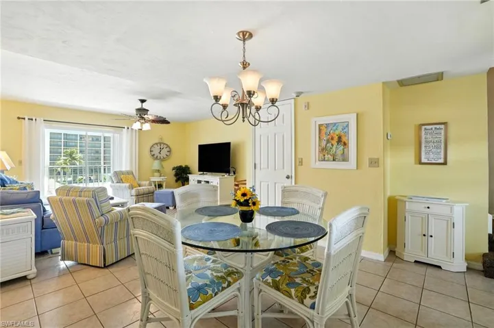 Dining area featuring light tile patterned floors, a chandelier, and a ceiling fan - Virtually Edited Image