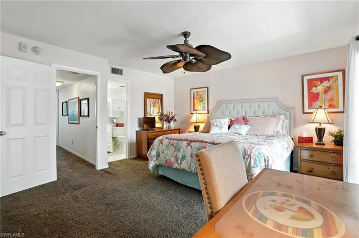 Carpeted bedroom featuring a ceiling fan and ensuite bath - Virtually Edited Image