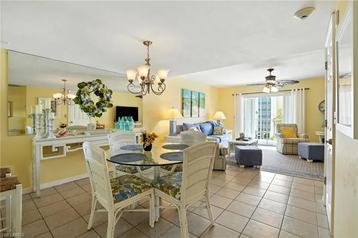 Dining area featuring light tile patterned flooring, a ceiling fan, and a chandelier - Virtually Edited Image