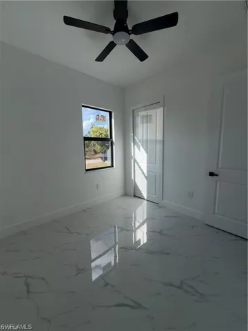 Bright room featuring high-gloss tile flooring, a dark-framed window, a ceiling fan, and a white paneled door with dark hardware