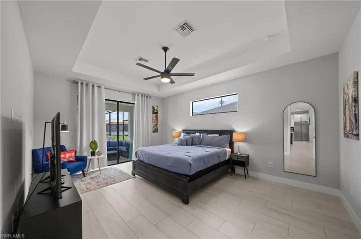 Bedroom featuring a raised ceiling, access to outside, ceiling fan, wood tiled floors, and arched walkways