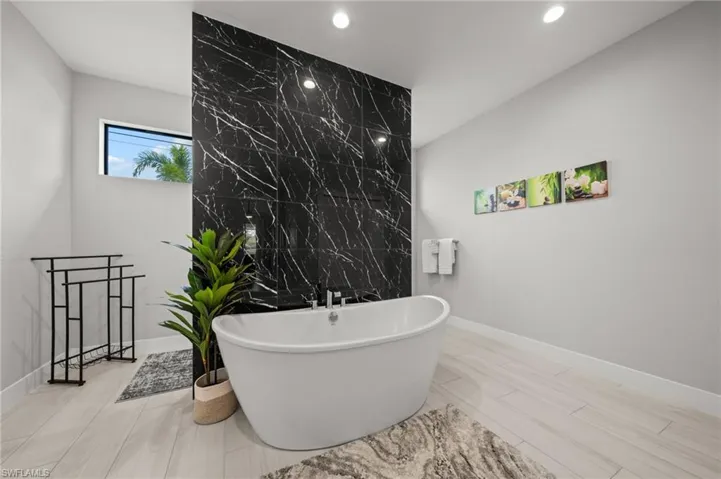 Bathroom featuring a freestanding bath, tile walls, and wood finish floors